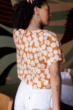 Load image into Gallery viewer, Back view of lady wearing a t-shirt with a patch on right side lower than hem of shirt.
