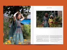 Load image into Gallery viewer, Magazine spread features photos of two ladies wearing gathered dresses with long loose fitting sleeves, amongst blocks of text.
