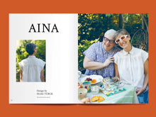 Load image into Gallery viewer, Two page spread features two ladies sitting at a picnic table wearing a capped sleeve collared blouse with front and back yokes, besides the text &quot;Aina&quot;
