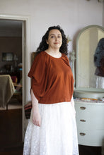 Load image into Gallery viewer, Model stands wearing a draped blouse with pleated scoop neckline
