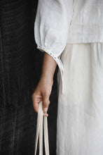 Load image into Gallery viewer, Close up detail of embroidered ribbons hanging untied off a sleeve cuff
