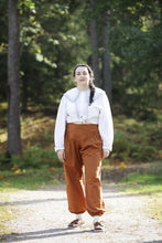 Load image into Gallery viewer, Model stands wearing a large collared button-up shirt, with trousers with a yoke waistband and gathered legs
