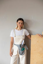Load image into Gallery viewer, Lady wears dungarees over a plain t-shirt, with a tool belt at waist
