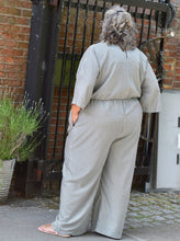 Load image into Gallery viewer, Back view of model wearing jumpsuit with hands in pockets
