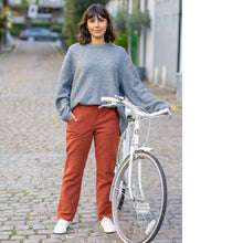 Load image into Gallery viewer, Lady stands next to bike wearing The City Trousers, a slim leg with hand in pocket
