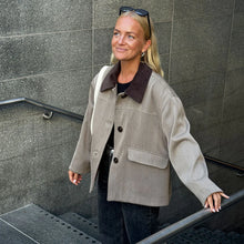 Load image into Gallery viewer, Model wears a short coat with contrasting fabric collar, front pocket flaps and three large buttons, walking up stairs
