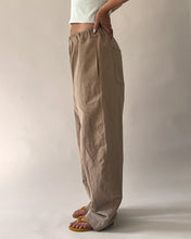 Load image into Gallery viewer, Side view of model wearing elasticated waist trousers with curved legs, and inseam pockets
