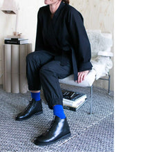 Load image into Gallery viewer, Lady sat on chair showing off her elastic cuff trousers and wrap jacket with royal blue socks and black shoes
