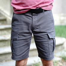 Load image into Gallery viewer, Man wears grey coloured cargo shorts with the patch pockets with flaps on the sides. Worn with a leather belt.
