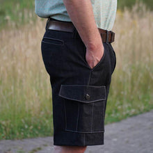 Load image into Gallery viewer, Side view of man wearing navy coloured cargo pants. Side pocket and flap with button. Seams sewn in a contrasting white colour thread.
