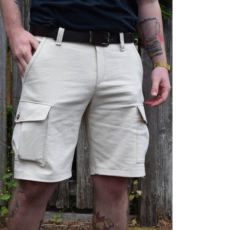 Man wears cream coloured cargo shorts with the patch pockets with flaps on the sides. Worn with a leather belt.