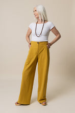Load image into Gallery viewer, Lady stands wearing wide-legged Mitchell Trousers, with hands on hips
