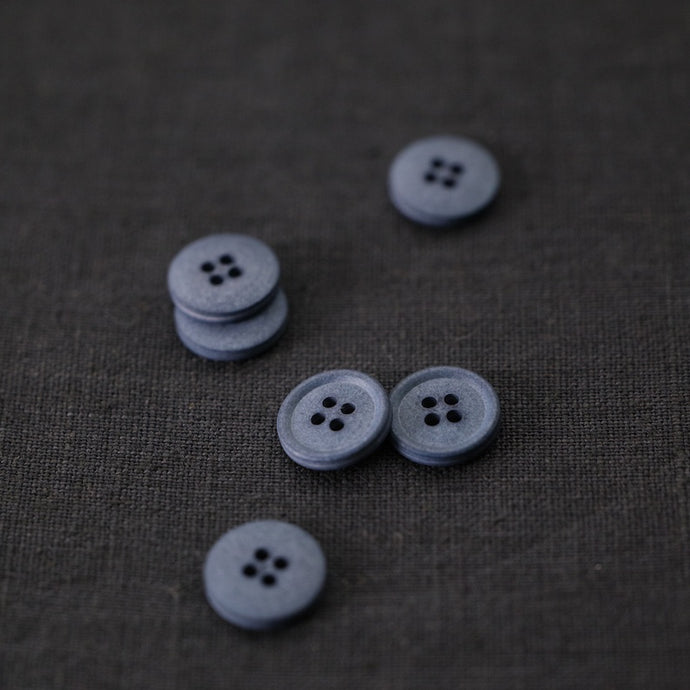 4-Hole Cotton Buttons scattered on top of linen fabric
