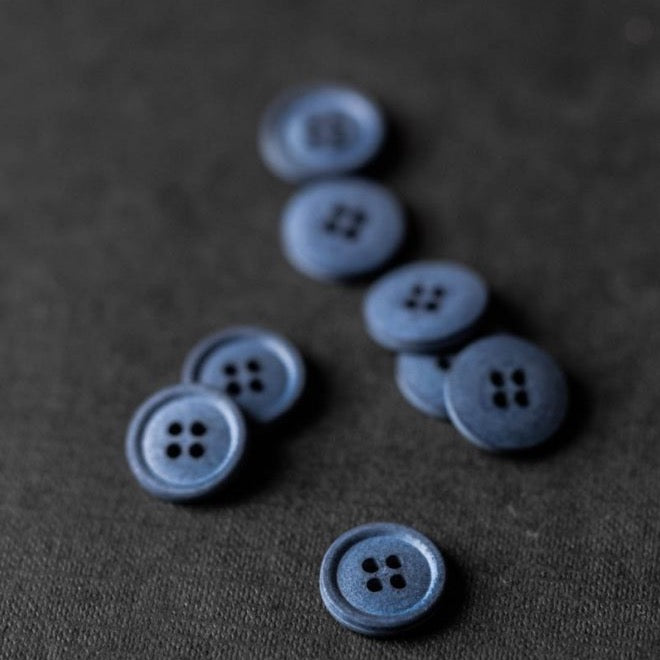 Dusty blue colour hard cotton buttons with four sewing holes.
