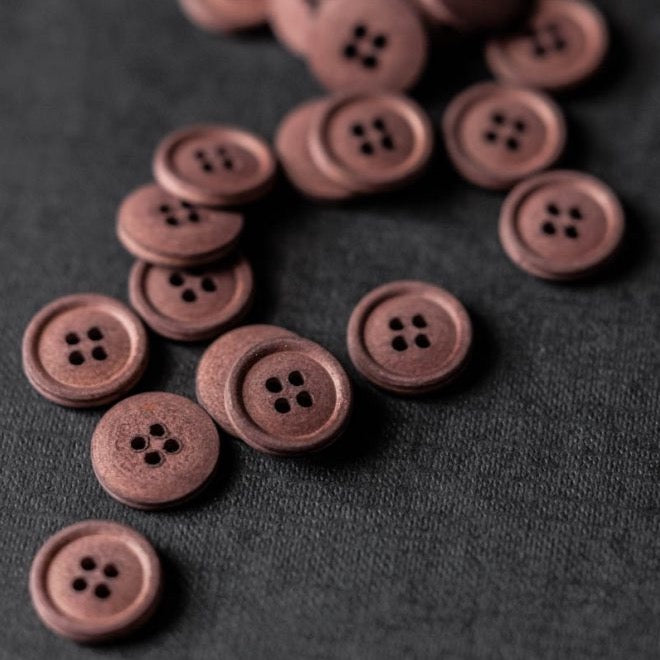 Group of dusty oxblood colour cotton buttons with four sewing holes.