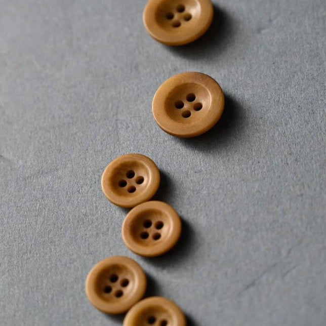 Gold/brown coloured wood-like buttons with four sewing holes.