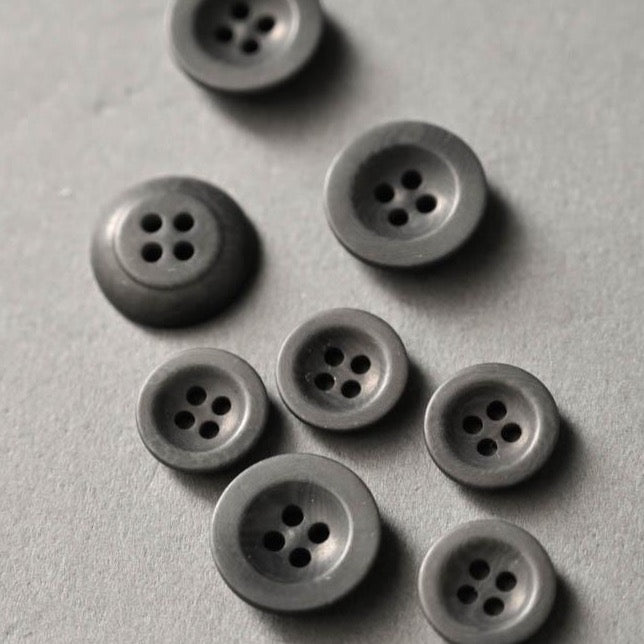 Grey coloured hard-resin-like buttons with four sewing holes.