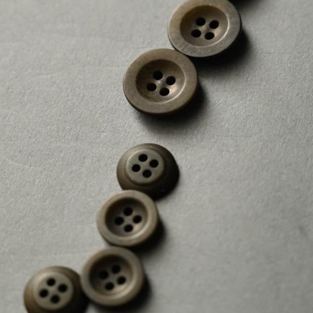 Dark green, khaki coloured hard-resin-like buttons with four sewing holes.