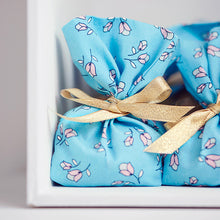 Load image into Gallery viewer, Close up view of small cubed packages wrapped in Lightening Lily Crystal Blue Cotton Fabric.

