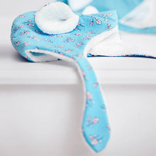 Load image into Gallery viewer, Baby&#39;s hat made with the Lightening Lily Crystal Blue Cotton fabric, laid on a table.
