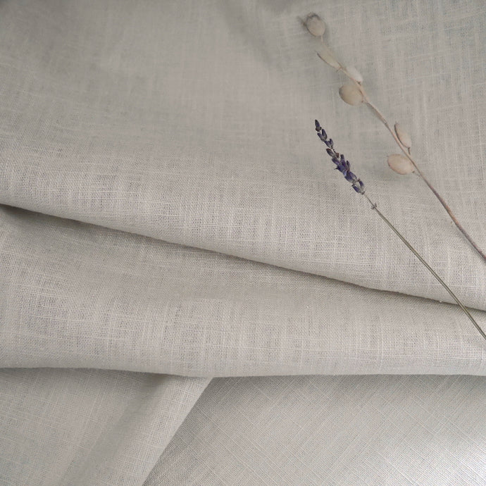Linen fabric in gentle folds with dried flower stems on top