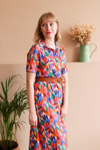 Load image into Gallery viewer, Lady stands wearing a button front, short sleeve dress made with Wonderland EcoVero Viscose fabric
