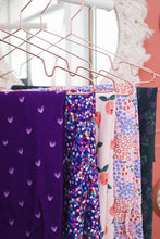Load image into Gallery viewer, Five fabrics in various patterns hang on hangers in a row
