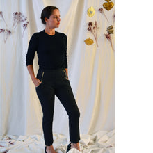 Load image into Gallery viewer, Lady standing wearing smart fitted LouLou trousers with white piping at pocket seams, with hands in pocket.

