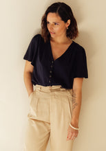Load image into Gallery viewer, Lady wears the Penelope Top tucked into trousers.

