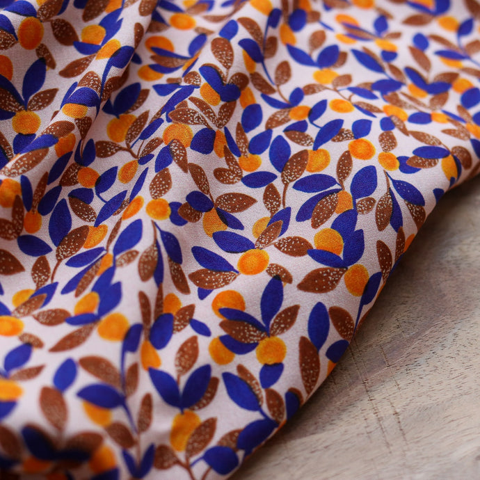 Close up of ruched fabric shows prints of repeated and crowded small mandarins with leaves