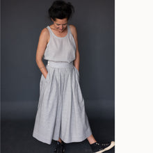 Load image into Gallery viewer, Lady wears a pleated Shepherd Pattern skirt with hands in pockets
