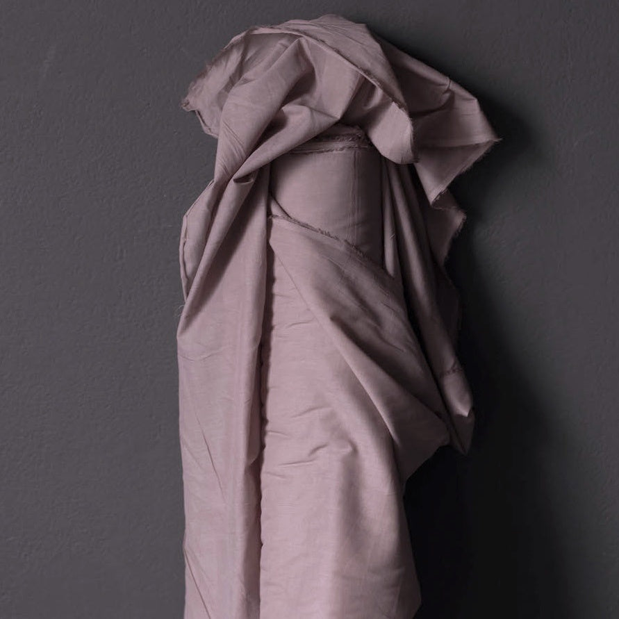 End of fabric roll stood against a wall with Organic Cotton Voile fabric draped over itself