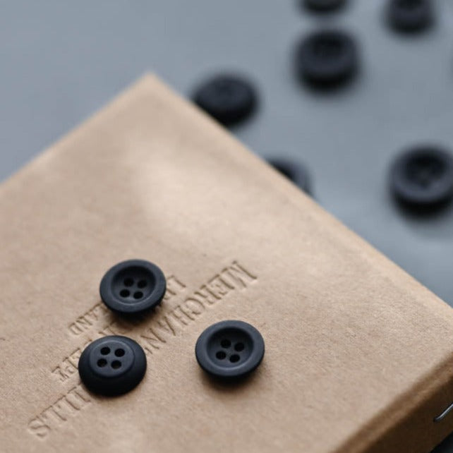 4-hole Corozo buttons displayed on a craft box, and scattered in the background