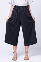 Load image into Gallery viewer, Front view of lady wearing Ninni Elastic Waist Culottes, holding the excess fabric by thighs out to show the looseness.
