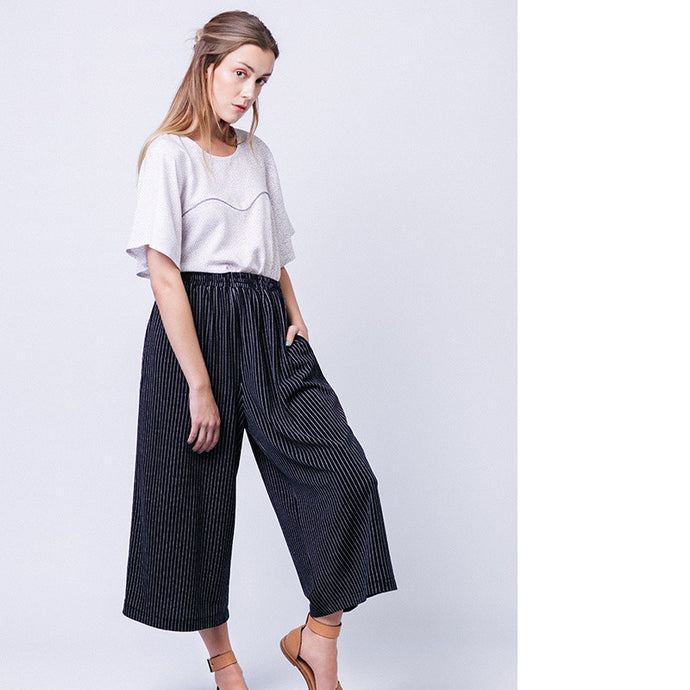 Lady standing, wearing elasticated waist culottes in a stripey fabric. Worn with a white t-shirt.