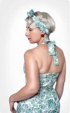Load image into Gallery viewer, Back view of lady wearing low back dress with halterneck strap. Headband of same green leaf print fabric.

