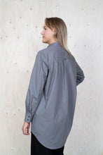 Load image into Gallery viewer, Back view of lady wearing oversized shirt in grey fabric. Shows cuff of long sleeve with two buttons.
