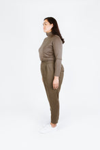 Load image into Gallery viewer, Side view shows lady wearing Guise Pants, inverted pleats at waistband, side pockets 
