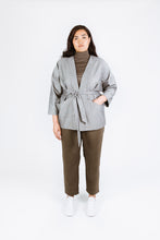 Load image into Gallery viewer, Lady wears Juno Jacket over a polo sweat. Jacket tied at waist, left hand in left front pocket
