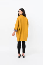 Load image into Gallery viewer, Back view of lady wearing Nova coat with sleeve folded up to show contrasting lining
