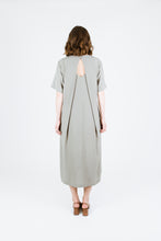 Load image into Gallery viewer, Back view of lady wearing Tide Dress showing two pleats overlapping a key-hole neckline
