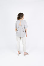 Load image into Gallery viewer, Back view of lady wearing Tide Top as a tee, shows off the pleats detail overlapping at the key-hole fastening at the centre front neckline
