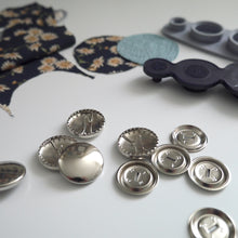Load image into Gallery viewer, 23mm metal cover button blanks displayed next to cover tool and circular pieces of fabric
