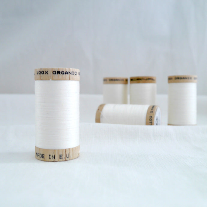 Collection of five wooden spools of organic cotton sewing thread in a Natural colour.