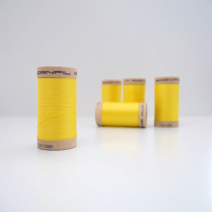 Four wooden reels of organic cotton sewing thread on table