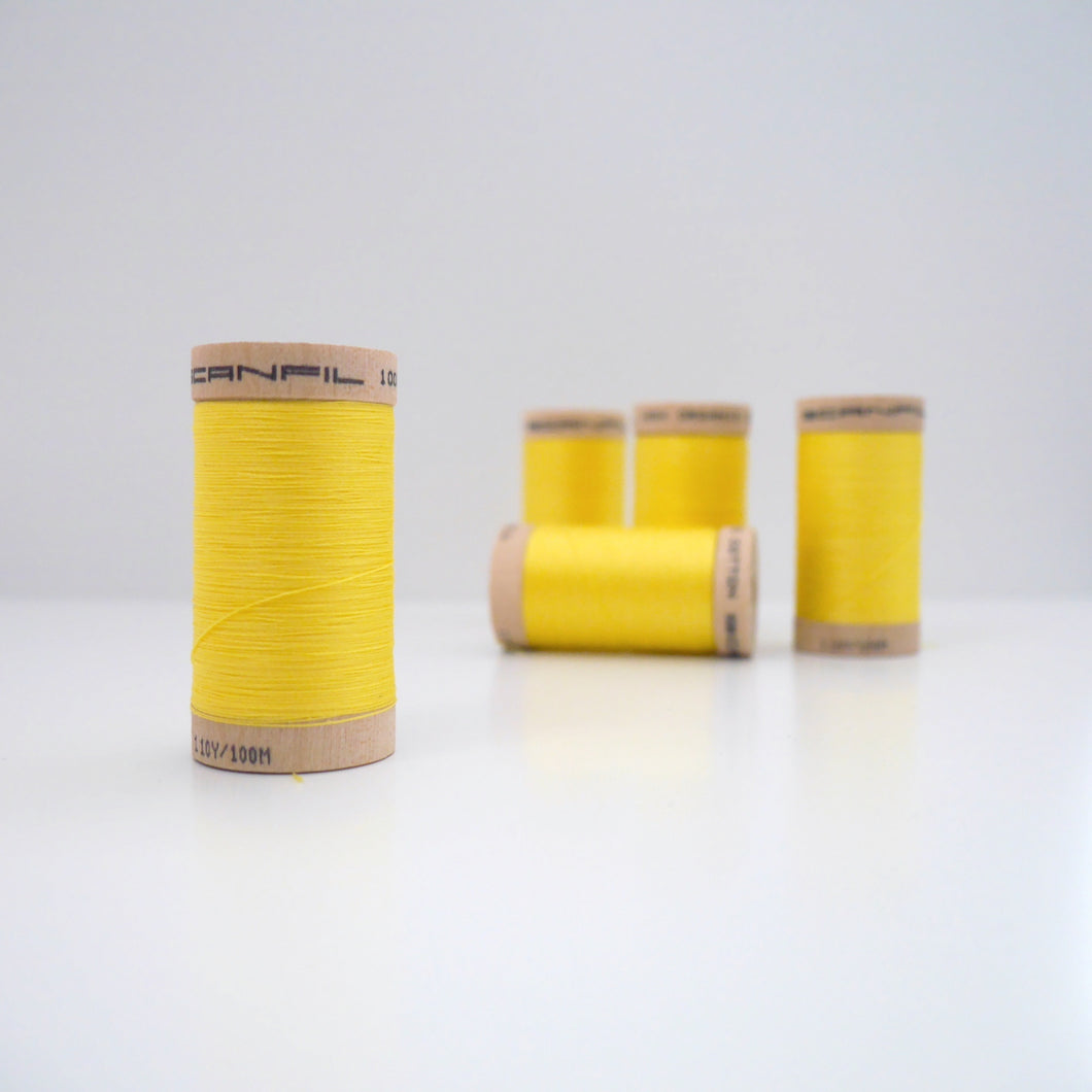 Four wooden reels of organic cotton sewing thread on table