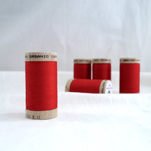 Load image into Gallery viewer, Collection of five wooden spools of bright red organic cotton sewing thread.
