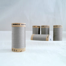 Load image into Gallery viewer, Five wooden spools of organic cotton sewing thread in Sand, a grey beige colour.

