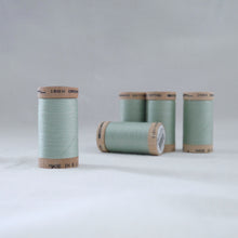 Load image into Gallery viewer, Four wooden reels of organic cotton sewing threads in a light mint green colour
