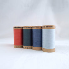 Load image into Gallery viewer, Four wooden reels of Scanfil Organic Cotton Thread in Salmon, Stormy Blue, Dusk, Ice colours.

